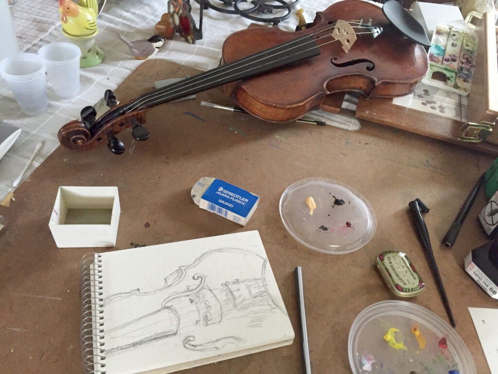 Violin on table with a drawing of it in progress, art supplies surround the paper